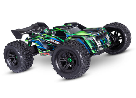 Traxxas 1/8 Sledge belted RC truck with green and RGB front tires, showing detailed close-up of the front wheel and tire tread.