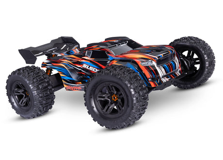 Traxxas 1/8 Sledge belted RC truck with orange front and RGB lighting, detailed view of the front side and tire.