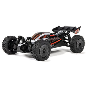 Silver ARRMA 1/14 Typhon GROM 223S DSC 4x4 RTR brushless buggy on off-road track, showcasing detailed design and rugged tires.